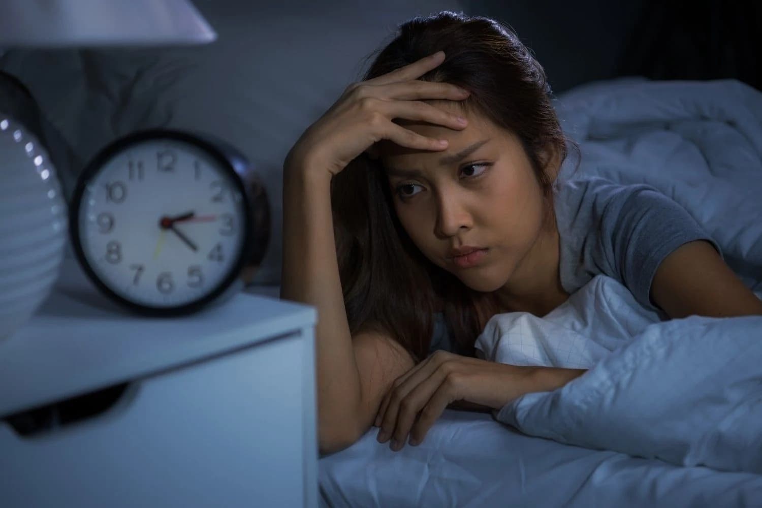 Why do I get sad at night? Person lying awake in bed feeling overwhelmed by nighttime sadness and racing thoughts