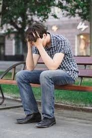 What Does It Mean When Someone Is Spiralling – man sitting on bench with head in hands showing emotional distress