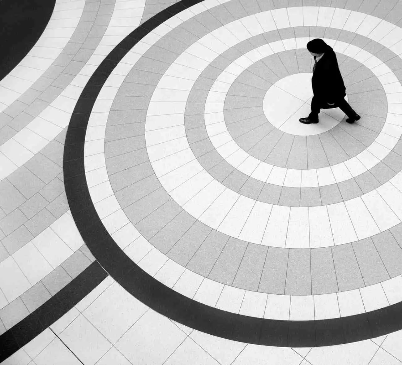 A person walking through concentric circles on a tiled floor, representing what happens in the brain during a spiral and the cycle of negative thought patterns