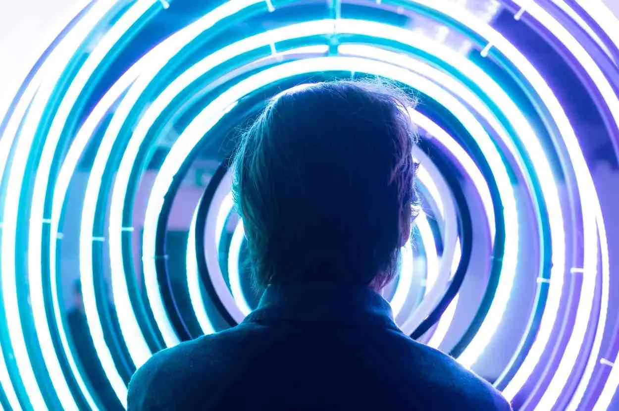 A person surrounded by glowing blue spiral rings representing why people spiral mentally and the causes of spiraling thoughts in mental health