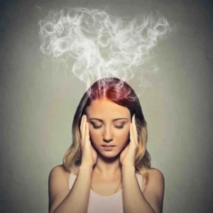 Woman holding her temples with eyes closed and steam rising from her head, symbolizing burnout vs depression and mental exhaustion from prolonged stress