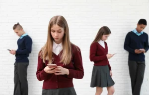 How is social media affecting teenagers shown by teens standing alone using smartphones and avoiding real-life interaction