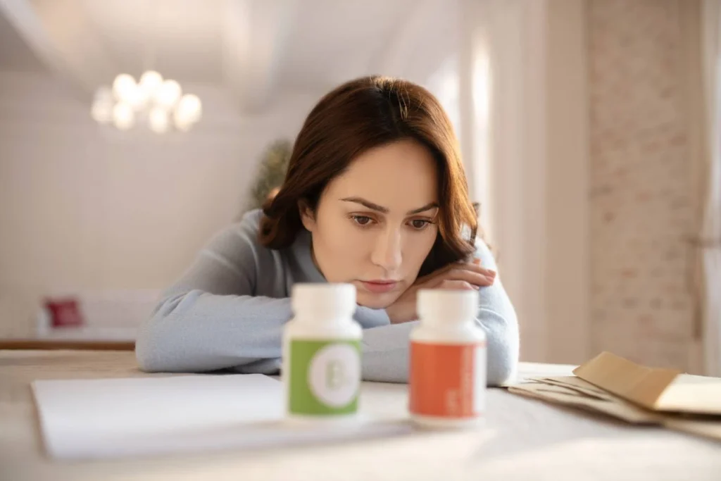 Woman looking at medication bottles on a table while Does Wellbutrin Help with Anxiety? and depression treatment