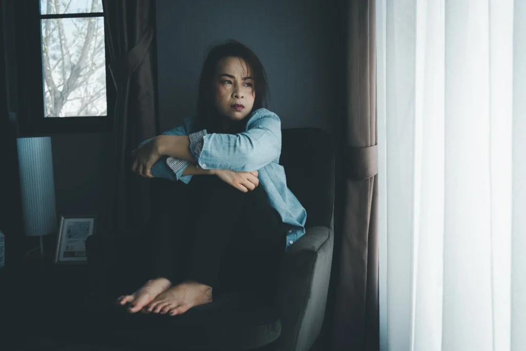Does depression ever go away? Person sitting alone by a window reflecting on depression recovery, emotional healing, and mental health treatment.