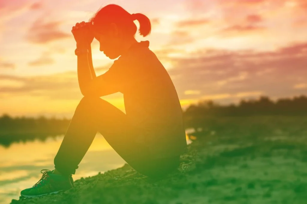 Person reflecting by a lakeside at sunset representing Trauma and Addiction Recovery, emotional healing, PTSD recovery, mental health support, and overcoming substance use disorder.