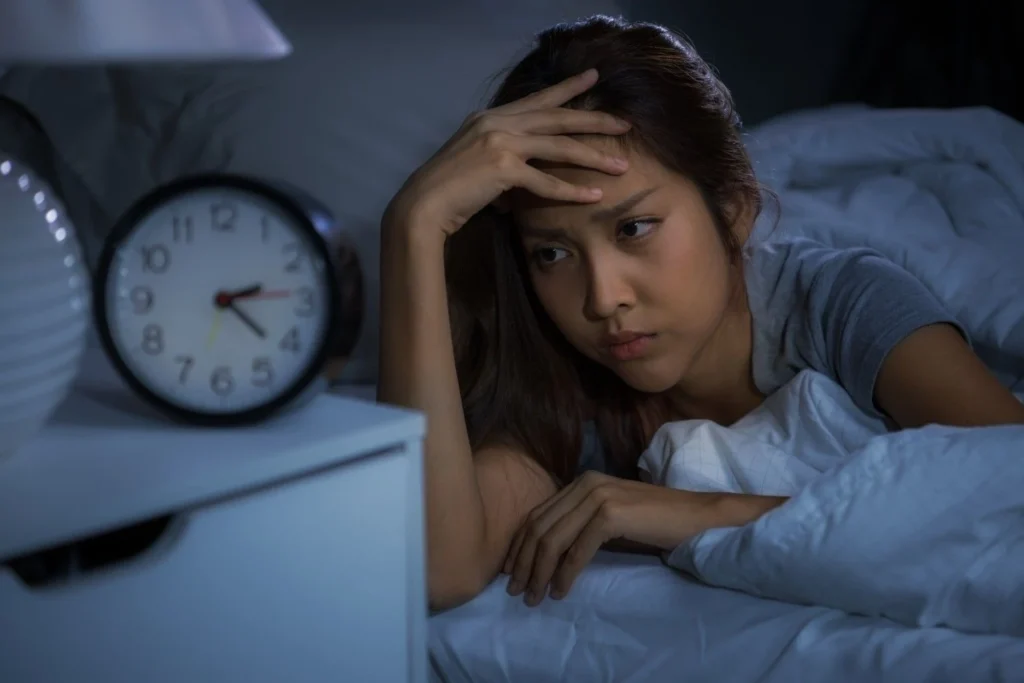 Why do I get sad at night? Person lying awake in bed feeling overwhelmed by nighttime sadness and racing thoughts